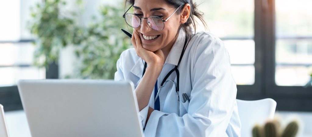 Shot,Of,Smiling,Female,Doctor,Working,With,Her,Laptop,In